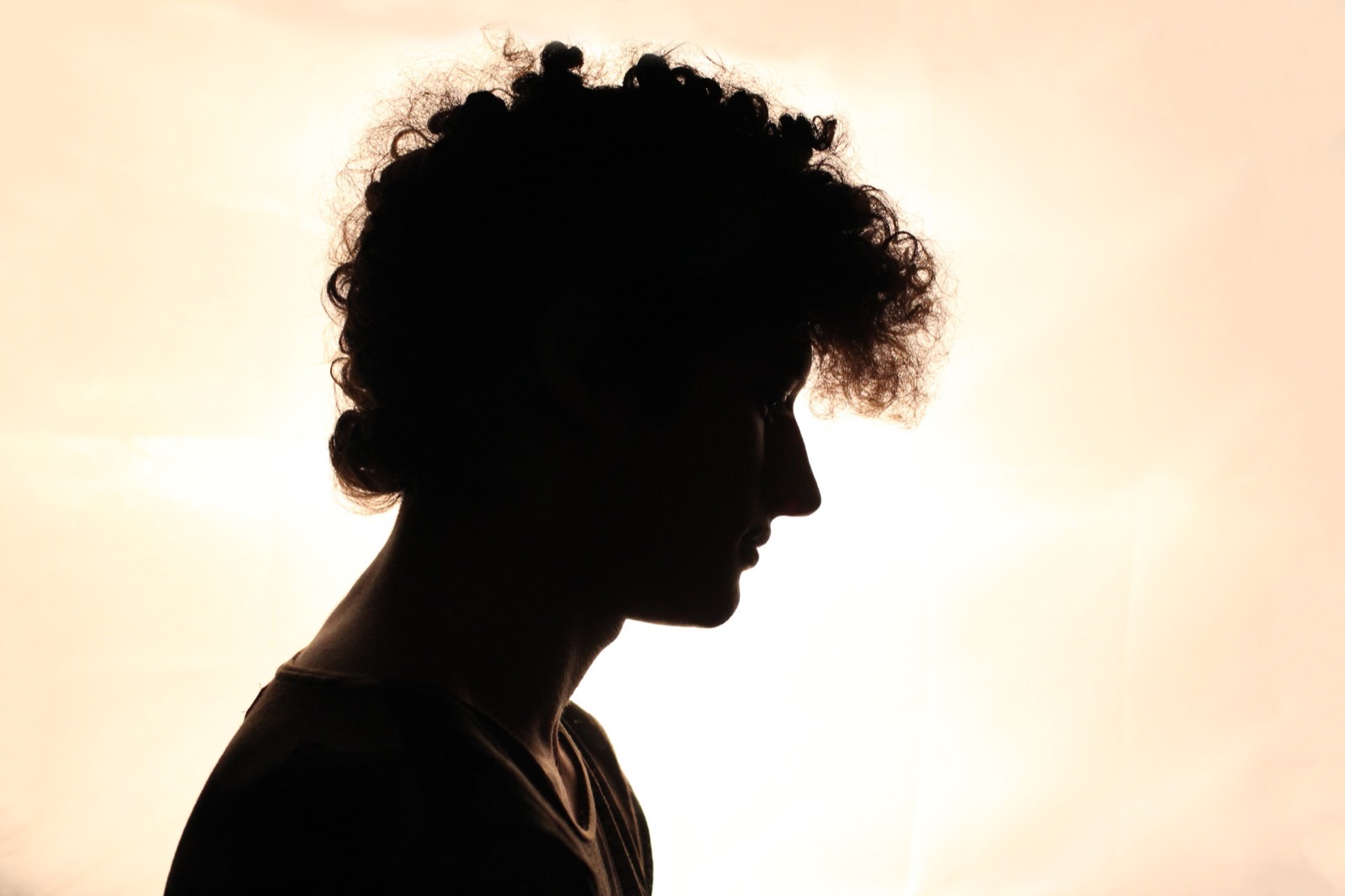 Backlit profile portrait of Francesco Lauriola in silhouette against a warm amber background.