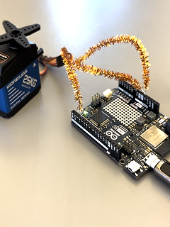 An Arduino UNO R4 WiFi wired to a 25 kg servo, a copper pipe-cleaner arm attached to the horn.